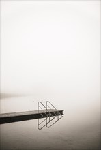 Empty bathing jetty in the morning mist at Irrsee