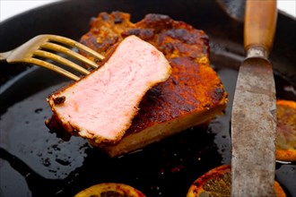 Pork chop seared on iron skillet with lemon and spices seasoning