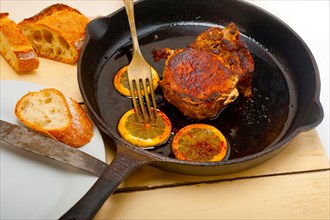 Pork chop seared on iron skillet with lemon and spices seasoning