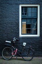 Bicycle parked at house wall in Amsterdam street. Bicycle is a famous very popular means of transport in Netherlands. Amsterdam