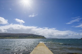 Concrete pier on sea with sun