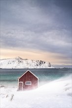 Red Rorbuer fishing hut on the beach in the snow