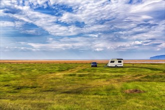 Single car with caravan in a meadow