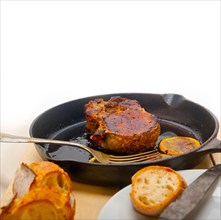 Pork chop seared on iron skillet with lemon and spices seasoning