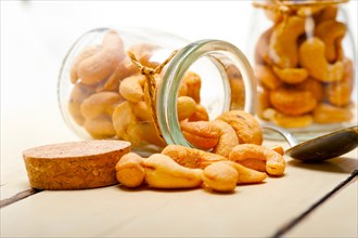 Cashew nuts on a glass jar over white rustic wood table