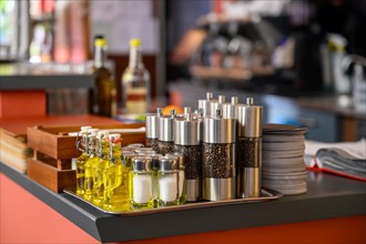 Salt and pepper shakers and small bottles of olive oil are placed on the counter of a restaurant