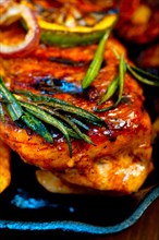Roasted grilled BBQ chicken breast with herbs and spices rustic style on iron skillet