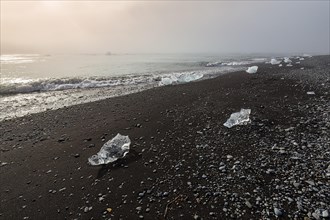 Ice crystals and pebbles on the black lava beach
