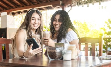 Two girls taking a selfie and drinking coffee