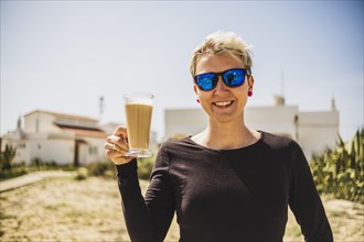 Happy woman with big coffee with milk during vacations in Portugal