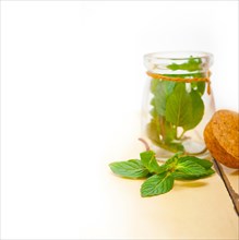 Fresh mint leaves on a glass jar over a rustic white wood table