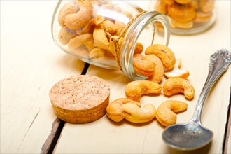 Cashew nuts on a glass jar over white rustic wood table