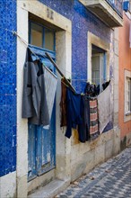 A house wall with blue tiles and a typical clothesline along the street in a village in Portugal