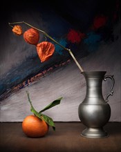 Still life with physalis in galvanised vase next to tangerine