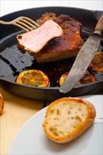 Pork chop seared on iron skillet with lemon and spices seasoning