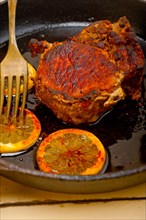 Pork chop seared on iron skillet with lemon and spices seasoning