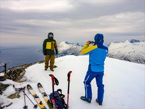 Ski mountaineer with Handi takes a summit photo on Flobjoern looking over the sea