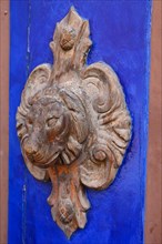 Lion's head as a doorknob on an old wooden door