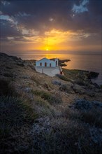 Small white Greek church by the sea at sunrise. Beautiful landscape shot with view to the horizon