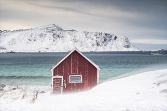 Red Rorbuer fishing hut on the beach in the snow