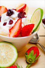 Fruit and yogurt salad healthy breakfast over white wood table