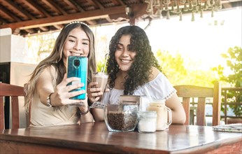 Two girls taking a selfie and drinking coffee