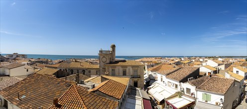 Above the rooftops of Saintes-Maries-de-la-Mer with a view of the church of Notre Dame de la Mer and the Mediterranean Sea in the background