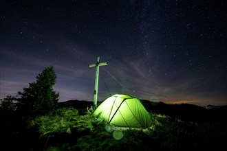 Green tent with summit cross under a starry sky on Portlakopf