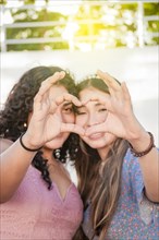Close up of two girls making a heart shape