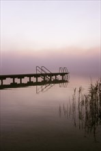 Empty bathing jetty in the morning mist at Mondsee