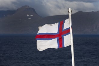 Flag of the Faroe Islands in front of the North Atlantic Ocean