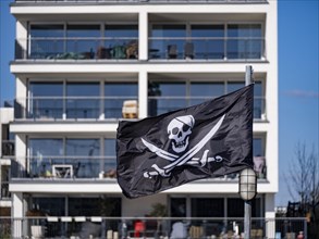 Pirate flag in front of condominiums in the new development Hafeninsel Mitte am Alten Hafen