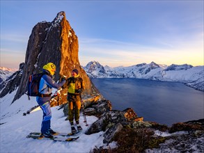 Two ski mountaineers congratulate each other on the steep mountain Segla