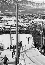 View of snow-covered Garmisch-Partenkirchen and the sixty thousand spectators in the ski stadium during the jumping from the small hill in the combination cross-country skiing