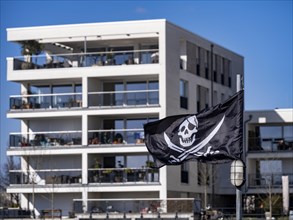 Pirate flag in front of condominiums in the new development Hafeninsel Mitte am Alten Hafen