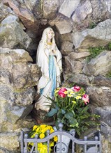 Virgin Mary figure with rosary and flowers