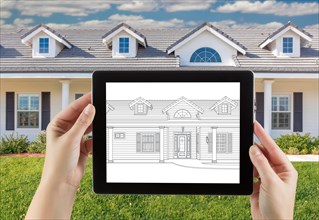 Female hands holding computer tablet with house drawing on screen