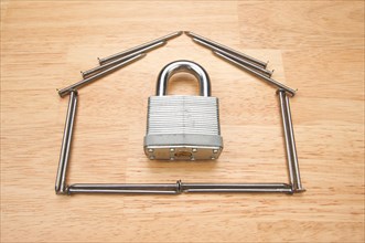 House of nails with lock on a wood background