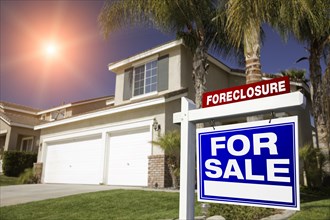 Blue foreclosure for sale real estate sign in front of house with red star-burst in sky