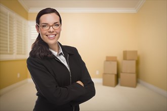 Attractive confident mixed-race woman in empty room with boxes