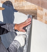 Worker smoothing wet pool plaster with trowel