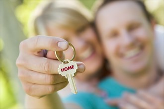 Happy couple holding house key with home text on the key