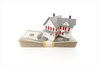 Small house on stack of hundred dollar bills isolated on a white background