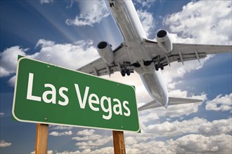 Las vegas green road sign and airplane above with dramatic blue sky and clouds
