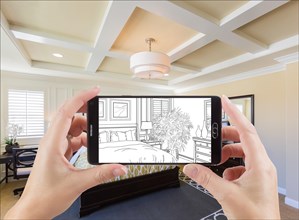 Hands holding smart phone displaying drawing of custom bedroom photo behind
