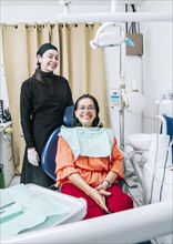 Dentist with patient smiling at camera in office
