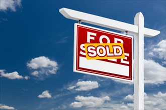 Left facing sold for sale real estate sign over blue sky and clouds with room for your text