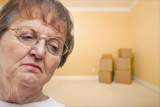 Sad older woman in empty room with boxes