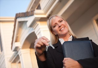 Female real estate agent handing over keys in front of beautiful house