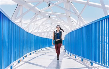 Urban girl walking on a bridge